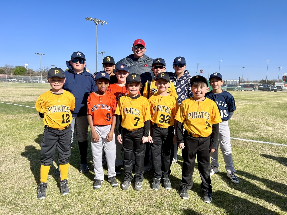 Snyder ISD superintendent poses with boys in little league uniforms on baseball field 