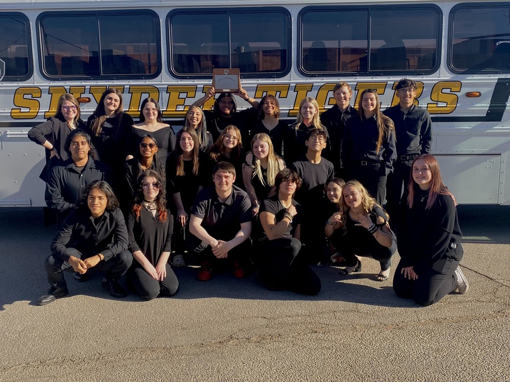 photo of choir students posing with plaque in front of bus
