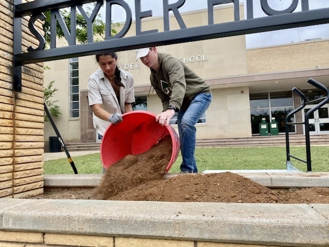 students adding flowers to SHS planter