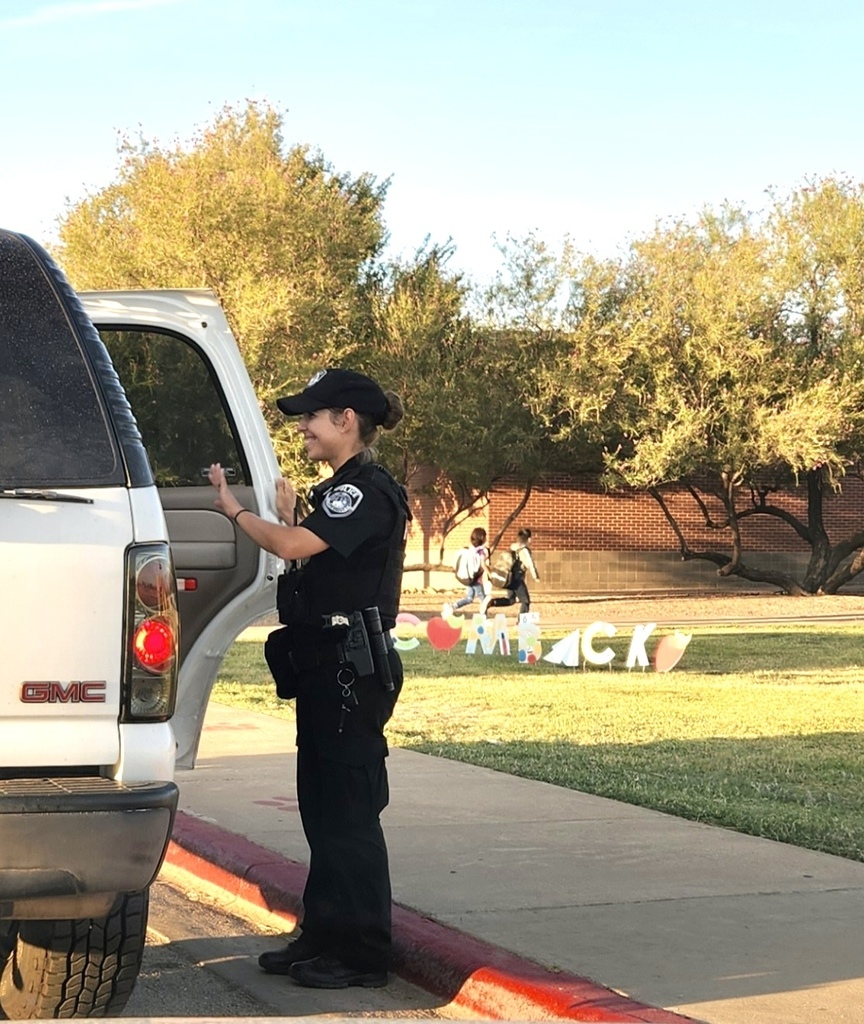 Police officer smiling and waving at students in the morning 