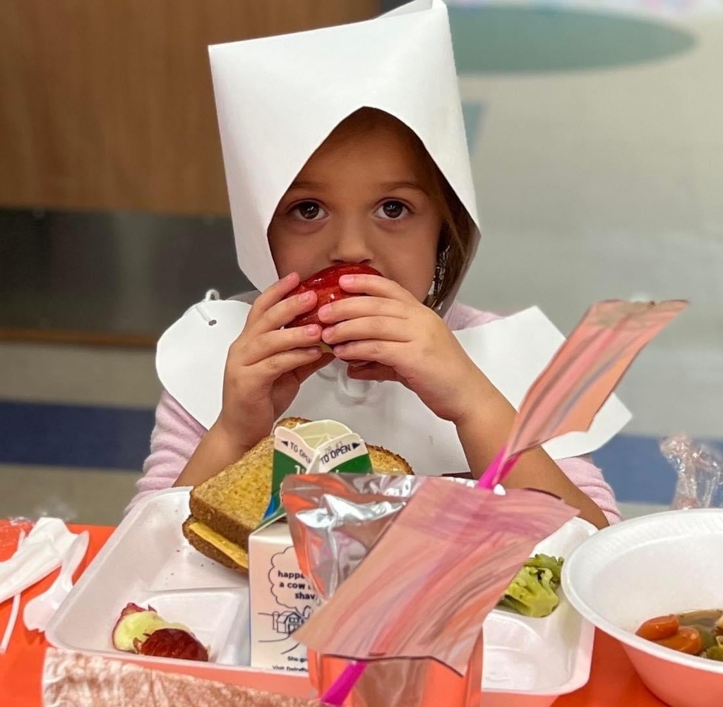 girl in pilgrim outfit eating an apple 