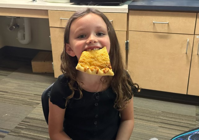Student smiling with pizza in her mouth