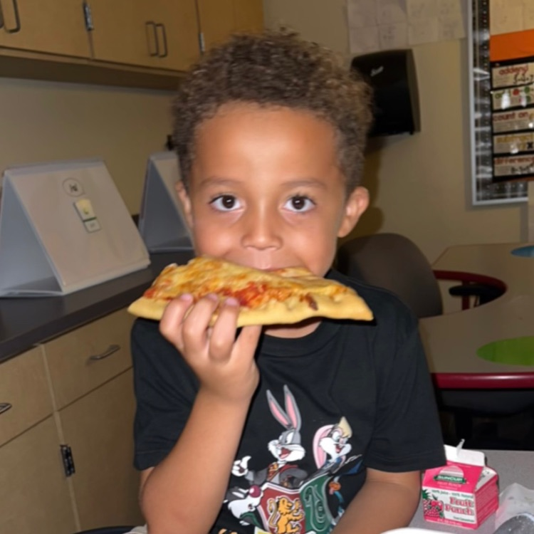 Student posing while eating pizza