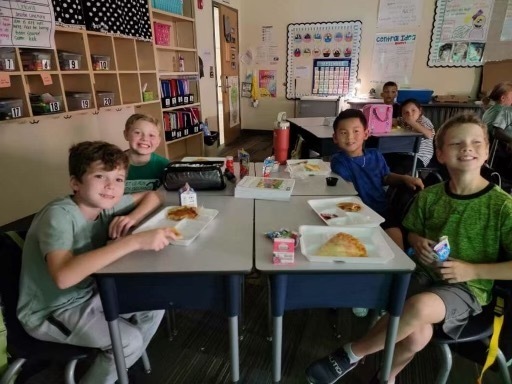 students at desk eating pizza